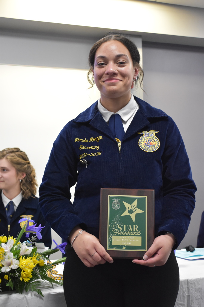 A student smiling at the camera with her award