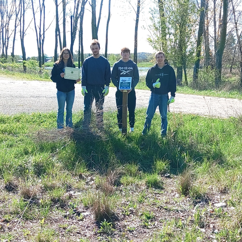 Students stand by rain garden