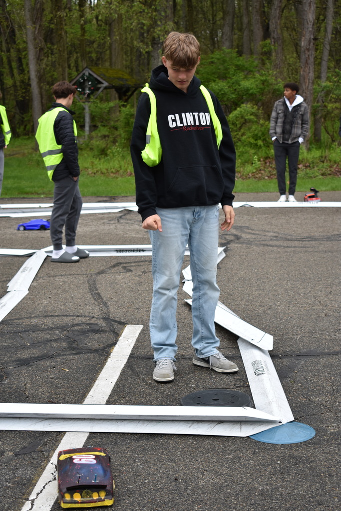 A student looking on to determine whether a car is stuck on the track while others are in the background 