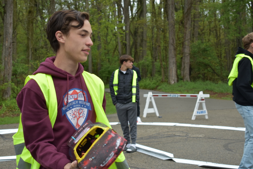 A student aiding a car that went off track while others look on 