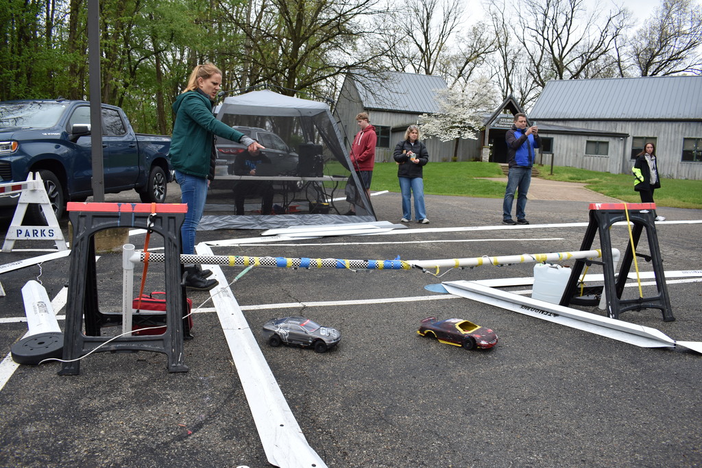 Two cars crossing the finish line while people look on