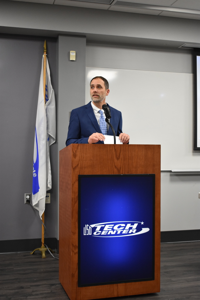 The instructor speaking at the podium