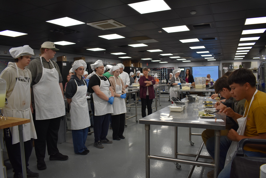 Students who cooked a dish watching the judges try it 