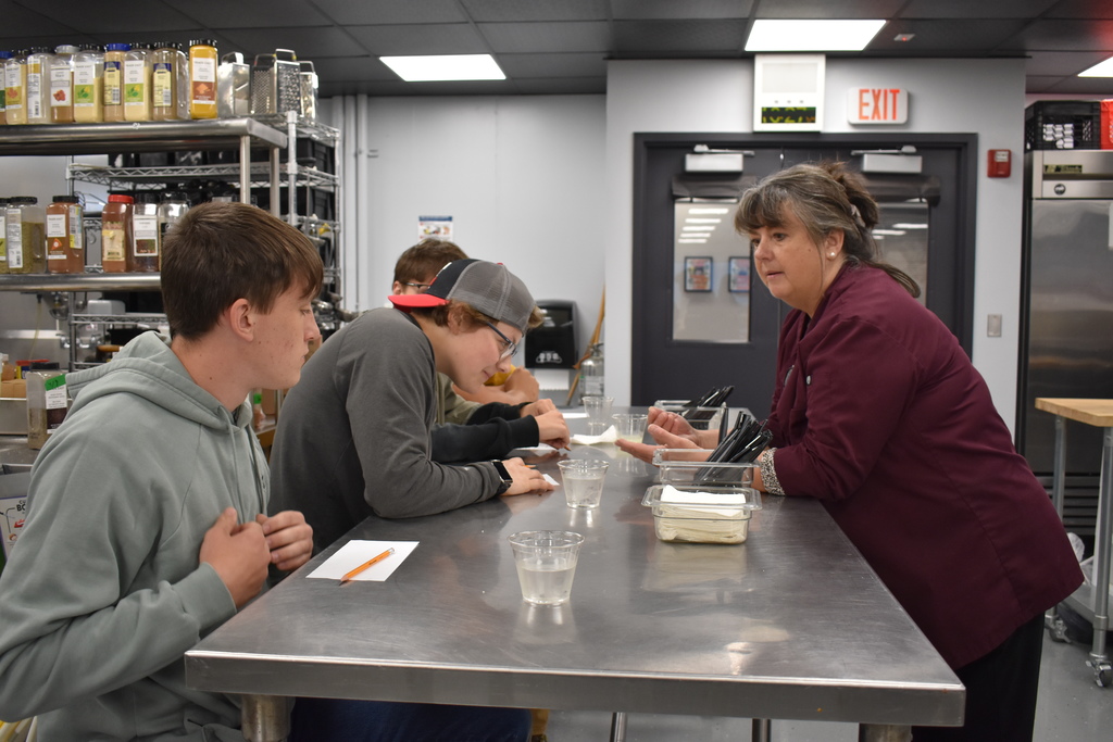 The culinary instructor giving directions to the am judges