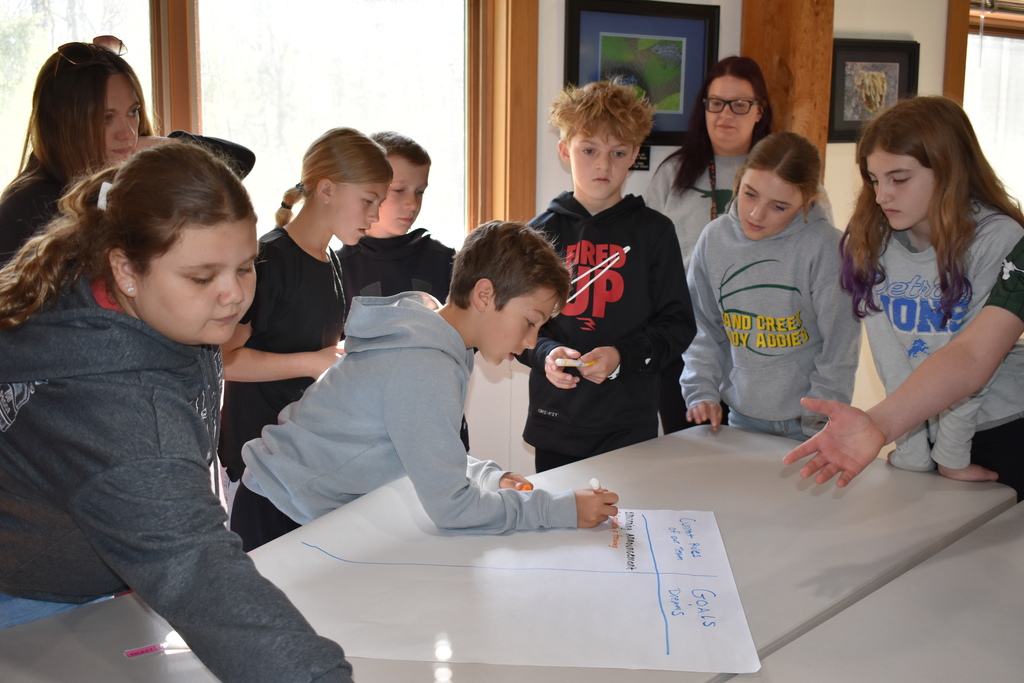 A student writing  down ideas while his classmates look on