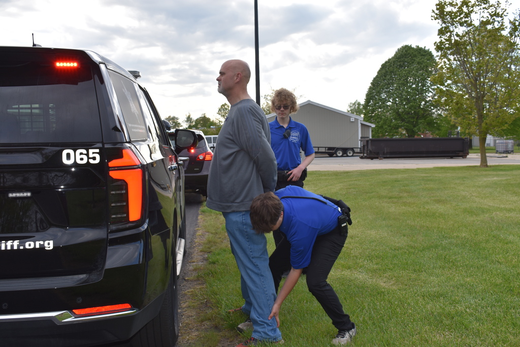 A student patting down someone to check for weapons