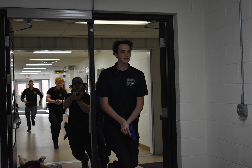 Students and a police officer searching for an active shooter in a demonstration