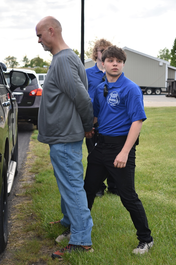 Two students preparing to place a gentleman in the back of a police car