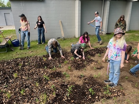 Natural Resources students spreading mulch around the native plants in their rain garden.