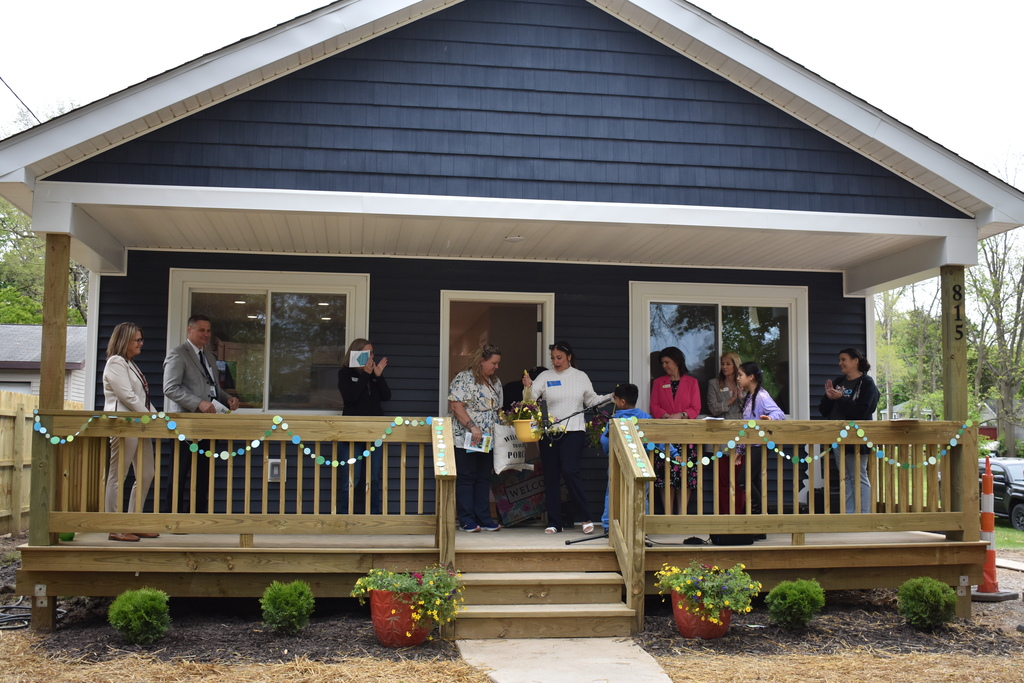 People standing on the porch of the home during the dedication