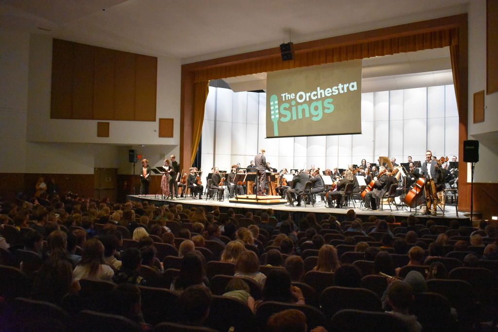 The orchestra on stage with an audience full of kids