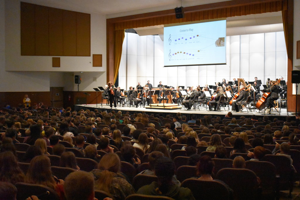 Orchestra on stage and students playing their recorders