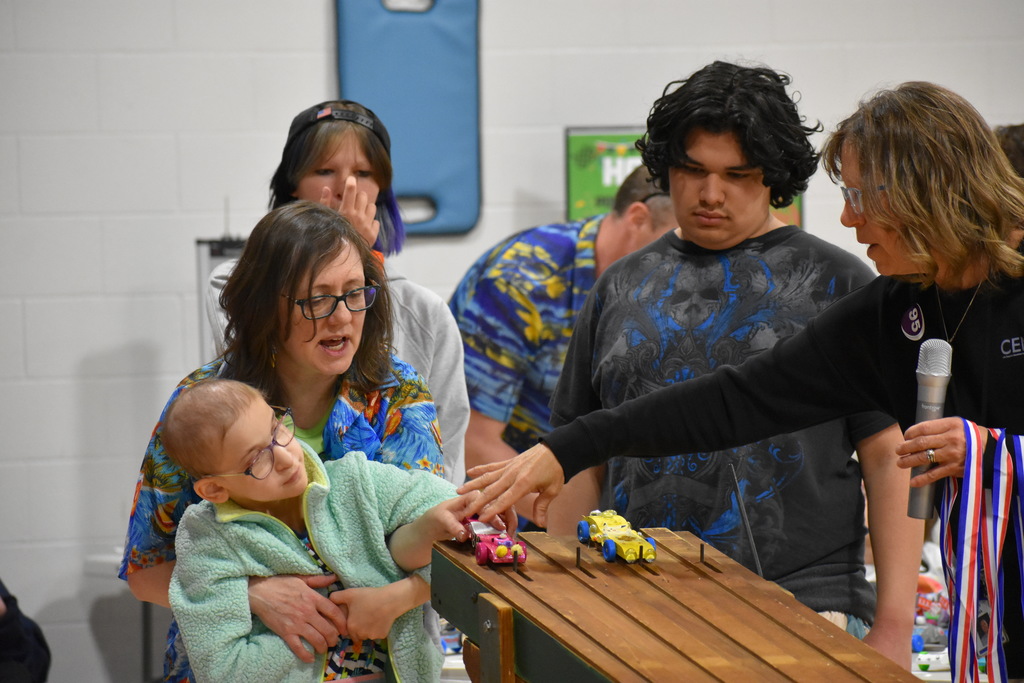 A teacher helping a student put her car up as a few students stand around