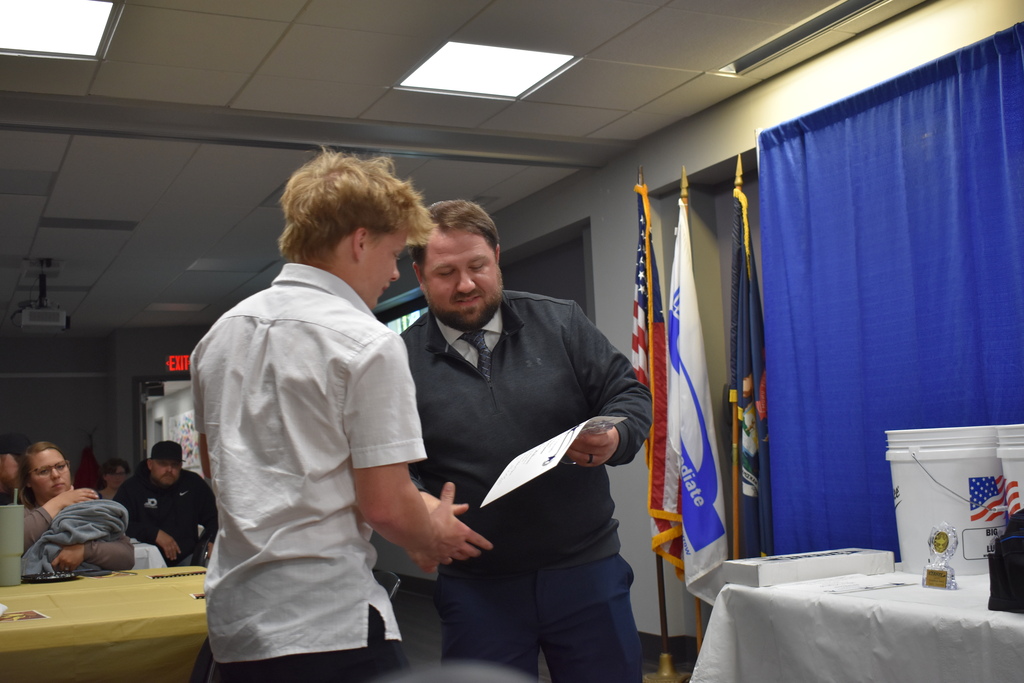 An instructor shaking the hand of a student award winner