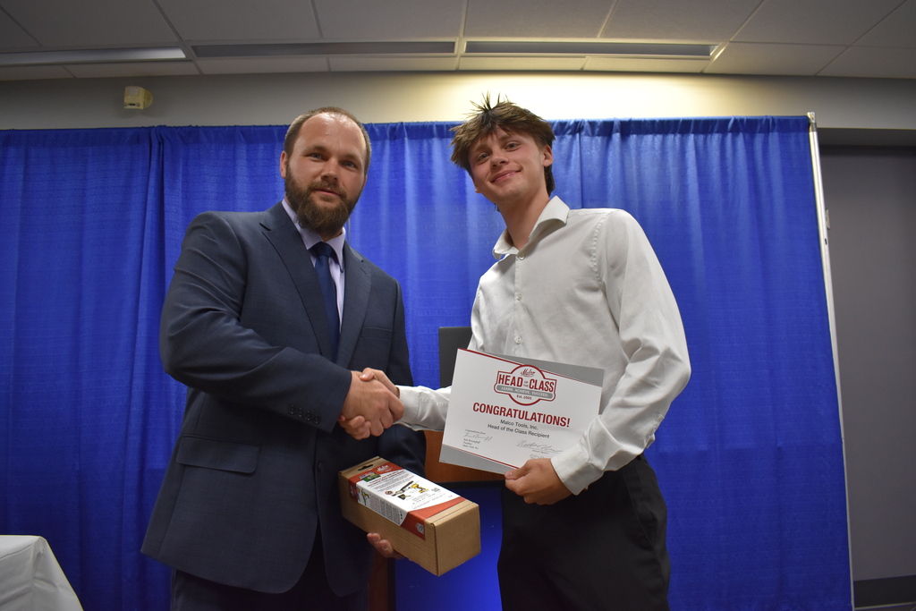 An instructor shaking the hand of a student award winner