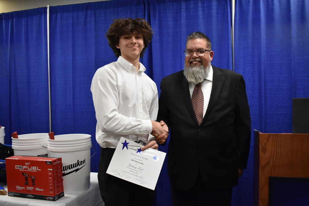 An instructor shaking the hand of a student award winner