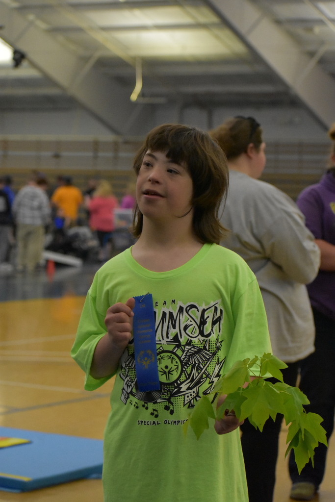 A student holds up his ribbon after a first place finish
