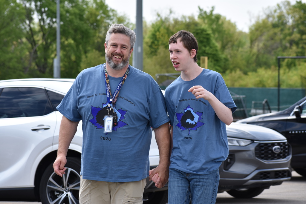 A student and teacher walk together and smile at the camera