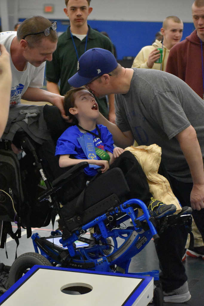 A father gives his son a kiss and a teacher congratulates a kid after a successful event