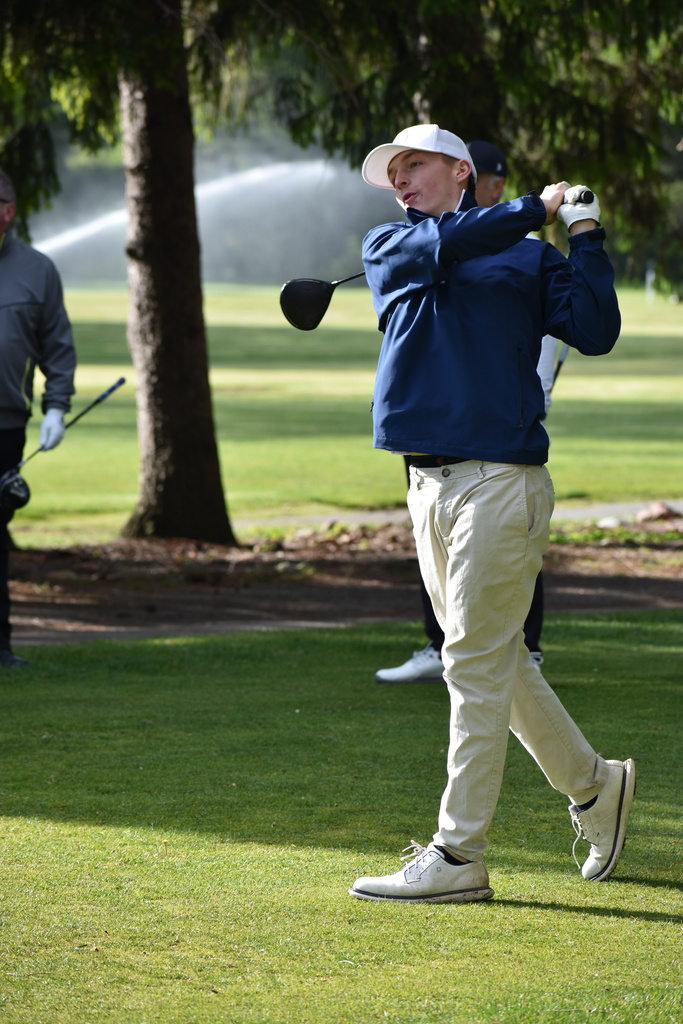 A student mid swing on the golf course