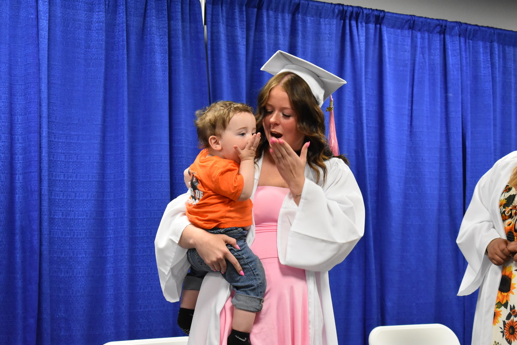 A graduate and her son blowing a kiss on stage