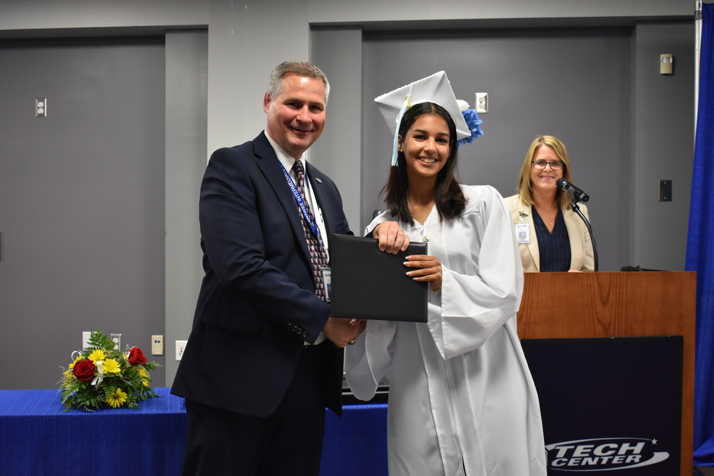 A graduate shaking the superintendent's hand while receiving her diploma