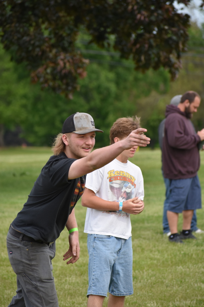 A student tossing a bean bag during cornhole with people in the background