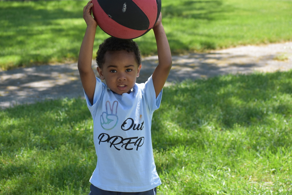 One of the students' children holding a basketball and wearing a t-shirt that reads "peace out PREP"