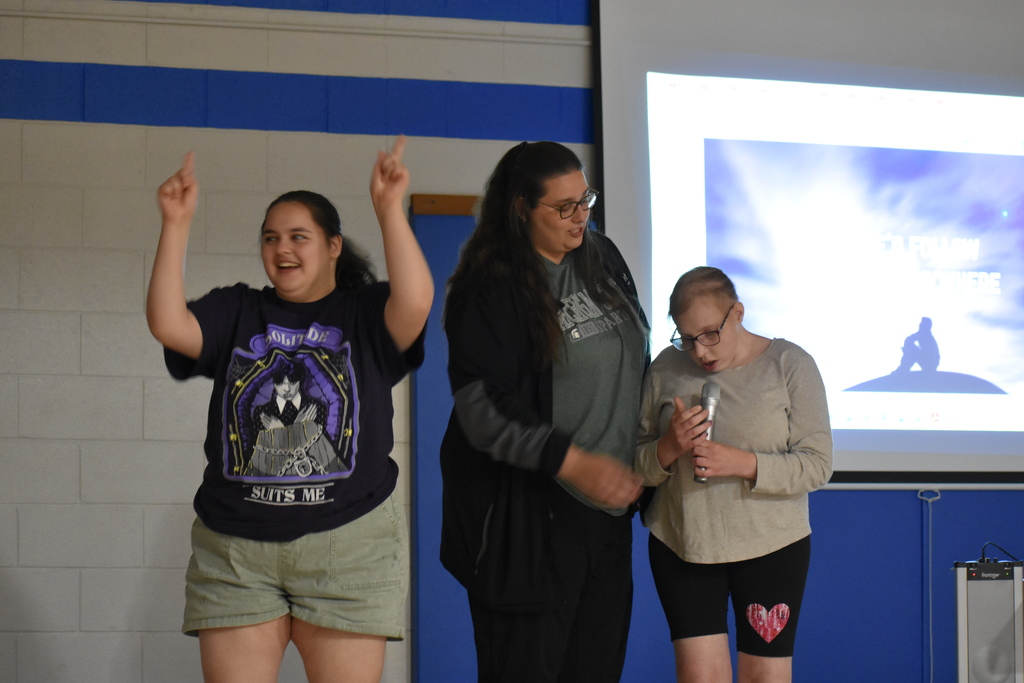 A student singing, a student dancing and a teacher helping with the mic