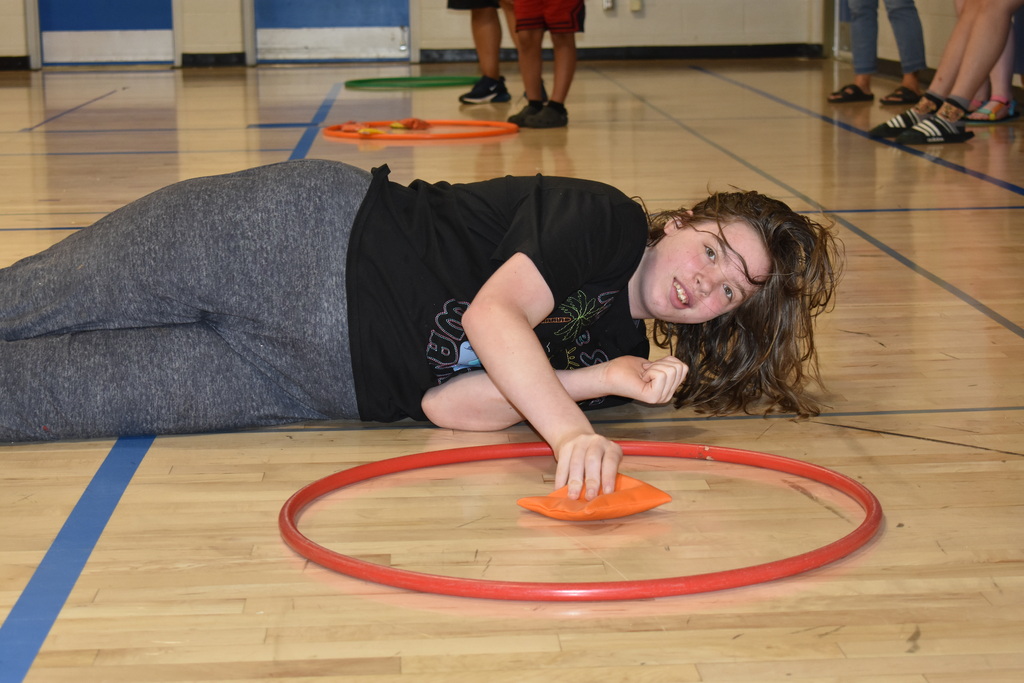 A student rolling on the ground for a game in the gym