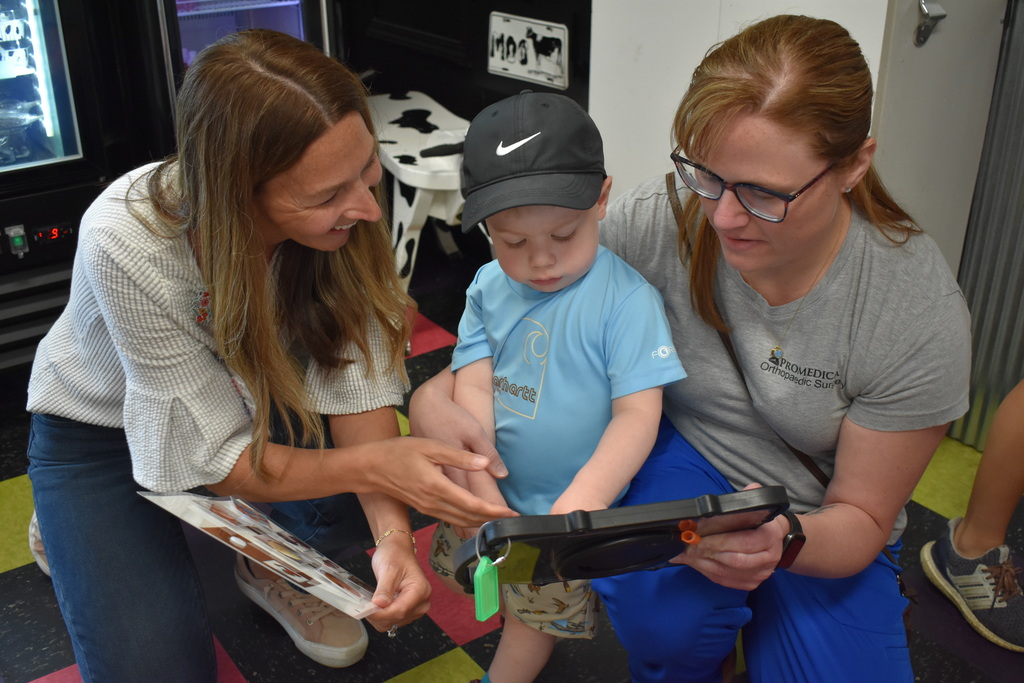 A parent, child and LISD employee using an AAC device to order ice cream