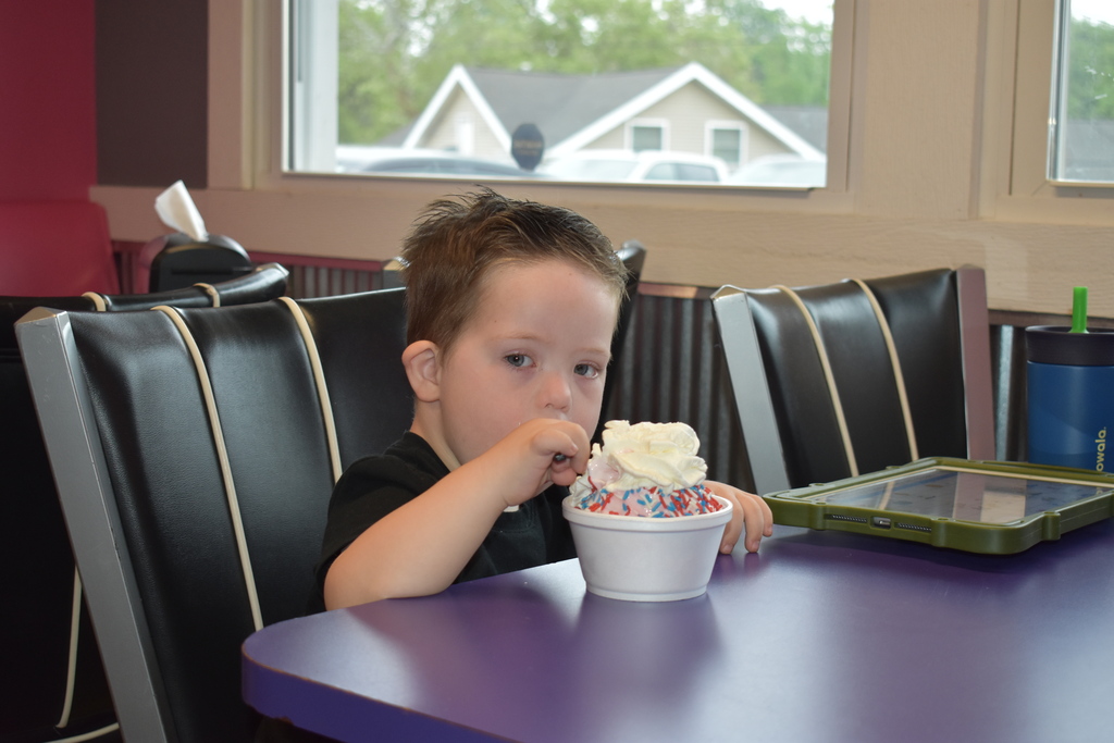 A child eating his ice cream with his AAC device sitting next to him