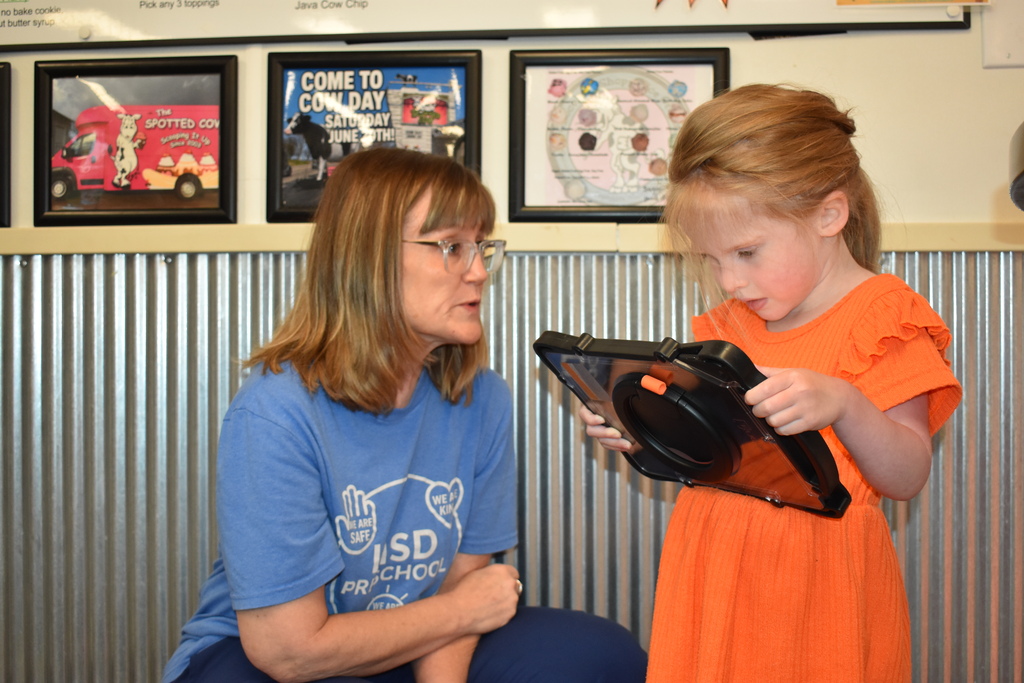 A child using an AAC device to order ice cream while an LISD employee looks on 