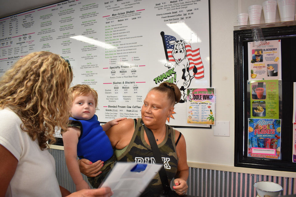 A parent, child and LISD employee using an AAC device to order ice cream