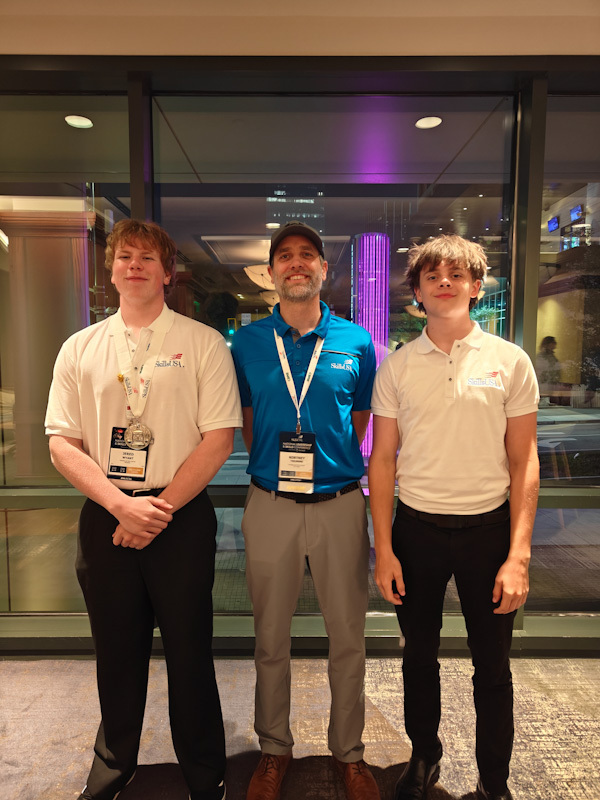 Two students posing for a photo with their instructor