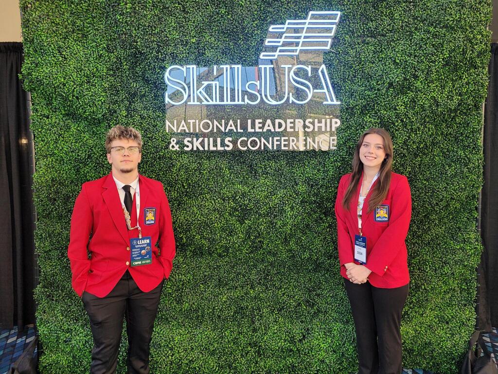 Two students posing in front of a SkillsUSA sign