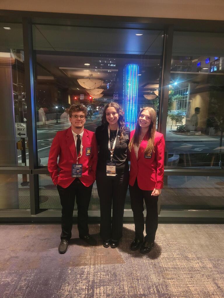 Two students with their teacher posing for a photo