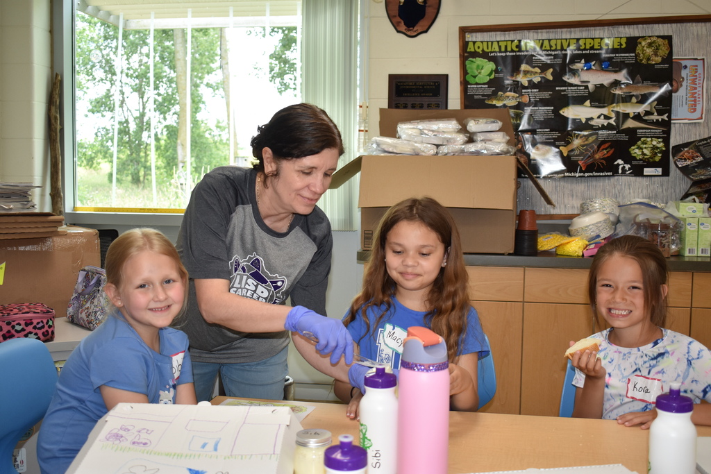 A teacher helping students spread their homemade butter on their bread