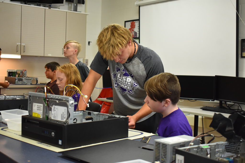 A teacher helping a studnt with a project with students in the background