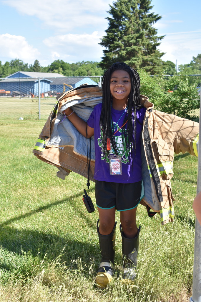 A young girl putting her firefighter coat on
