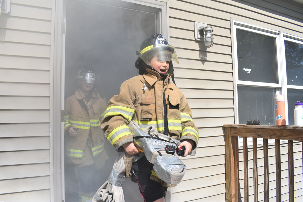 Two Junior Firefighters coming out of a smoke filled house