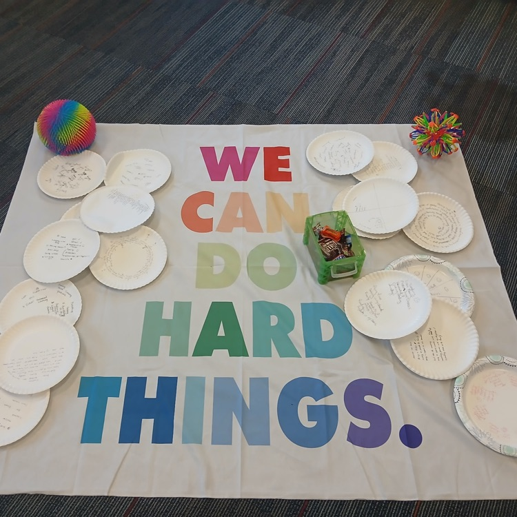a banner that reads “we can do hard things” with writing on plates from the participants