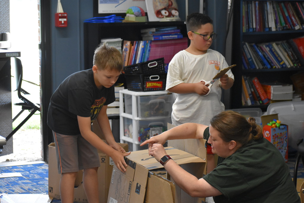 Two students and a teacher working on a box construction project