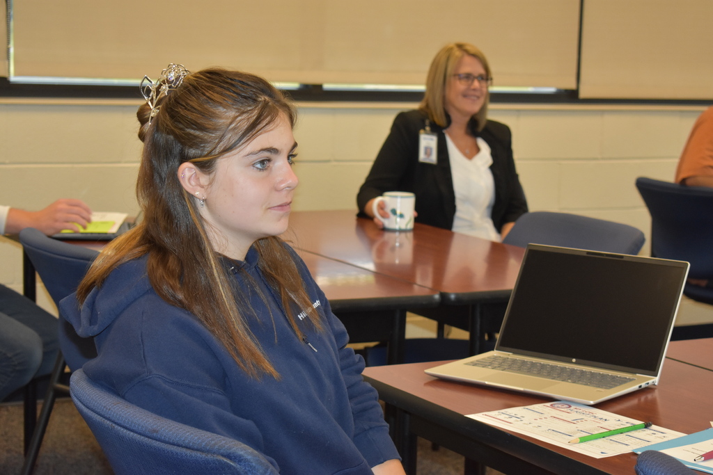 A student listening to someone speaking with a staff member in back