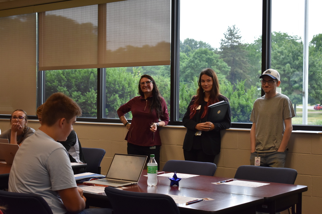 A student and staff sitting and standing in the room