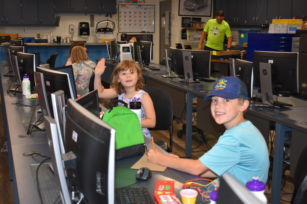 Two students working with their circuit boards and smiling at the camera