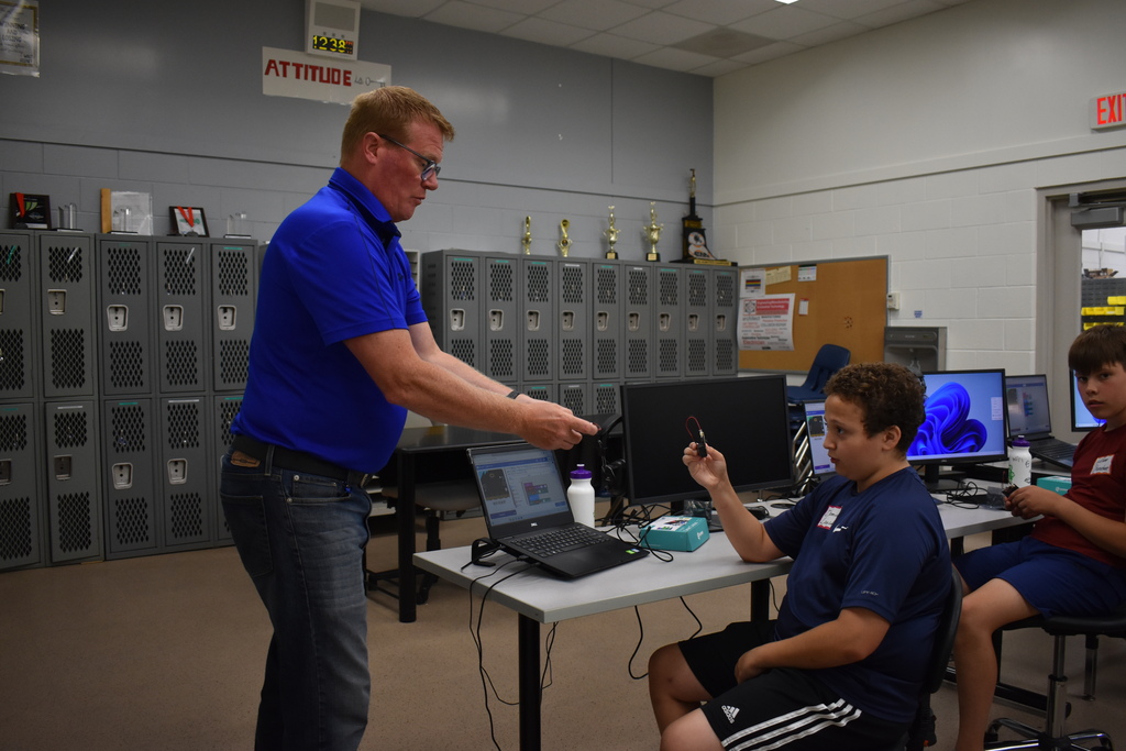 An instructor and a student playing a game of rock, paper, scissors using a robot