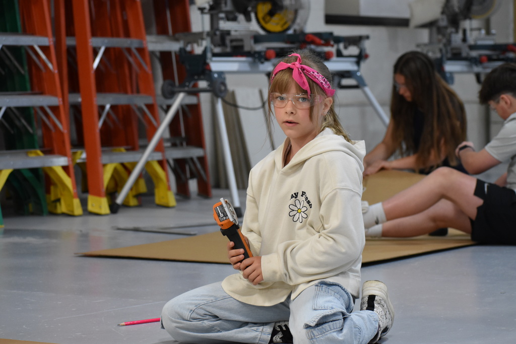 A young girl holding a saw