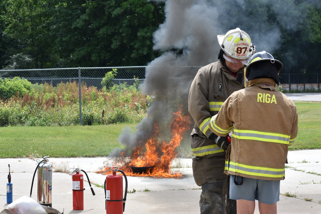 A firefighter gearing up a junior firefighter to fight a fire