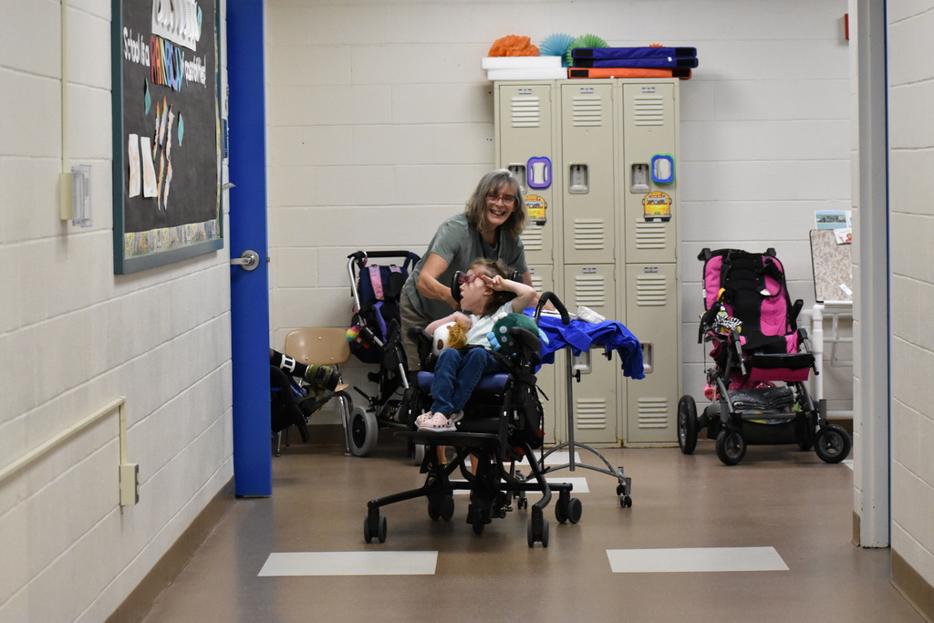 A teacher wheeling a student down to another classroom